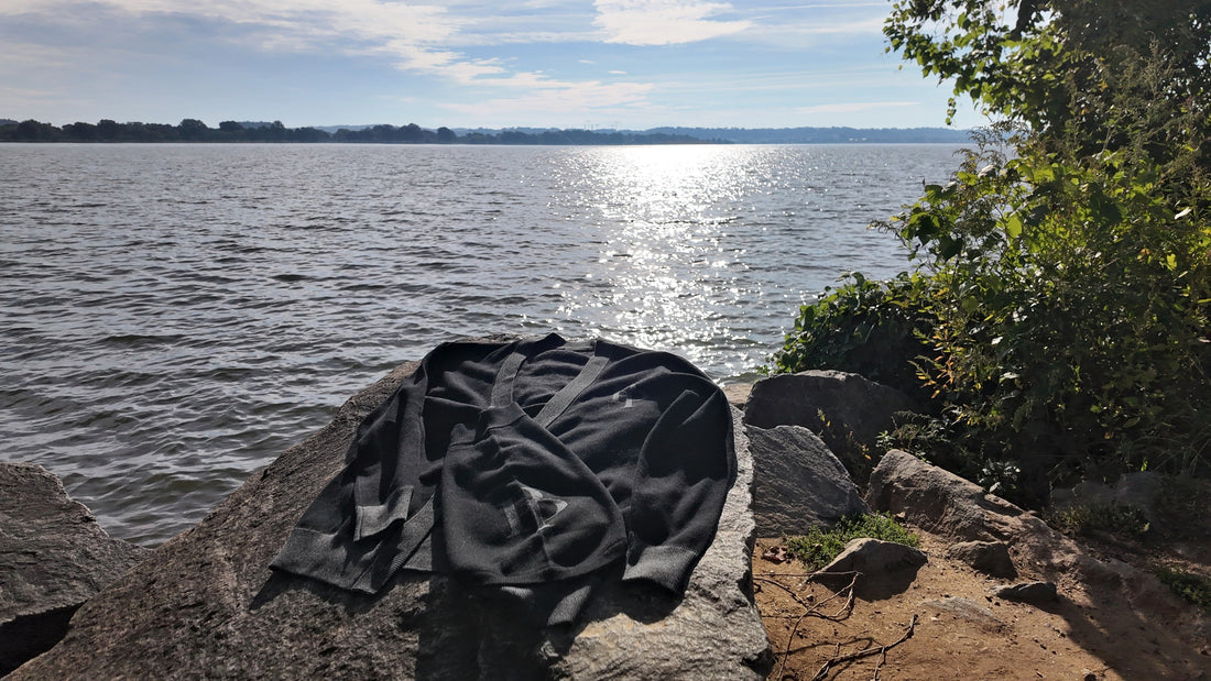 Onyx & Graphite cardigan laid on a rock by the water