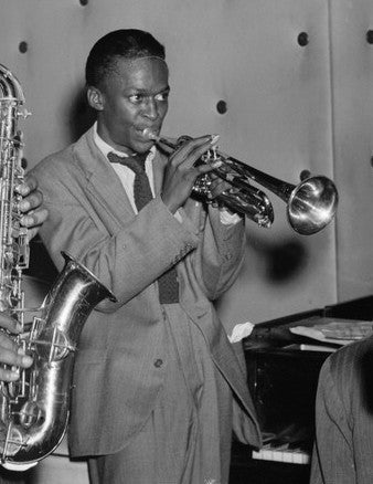 Miles Davis playing trumpet in a light double-breasted suit in New York in 1947