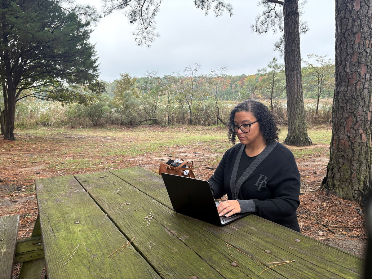 Onyx monogram cardigan worn while working outdoors at a lakeside picnic table