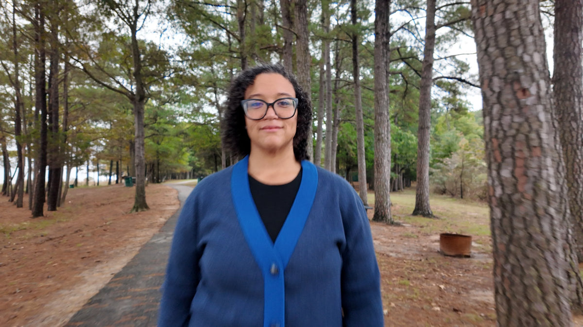 Navy and collegiate blue cardigan walking through pines