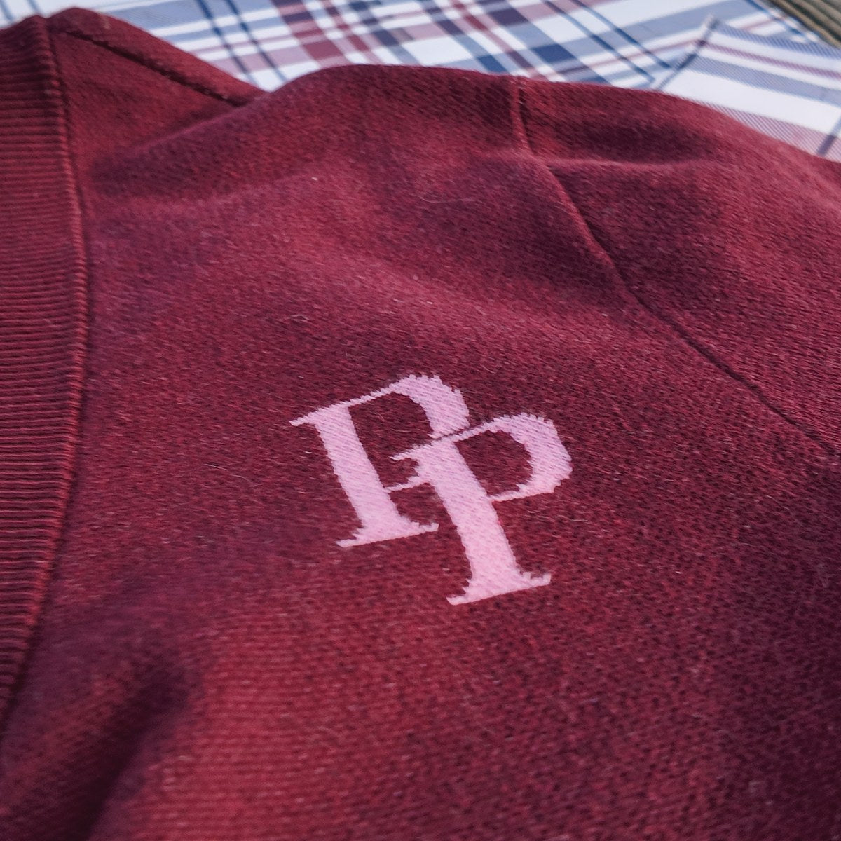 A rose pink PP monogram on a burgundy cardigan