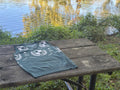 Green crest V-neck sweater vest on a wooden table by the water