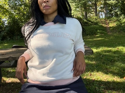 Anissa wearing the Selective sweater seated outdoors